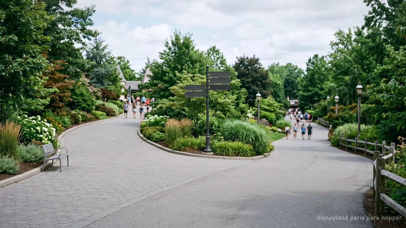 A fork in a wide paved park walkway between two landscaped areas, visitors distant and blurred