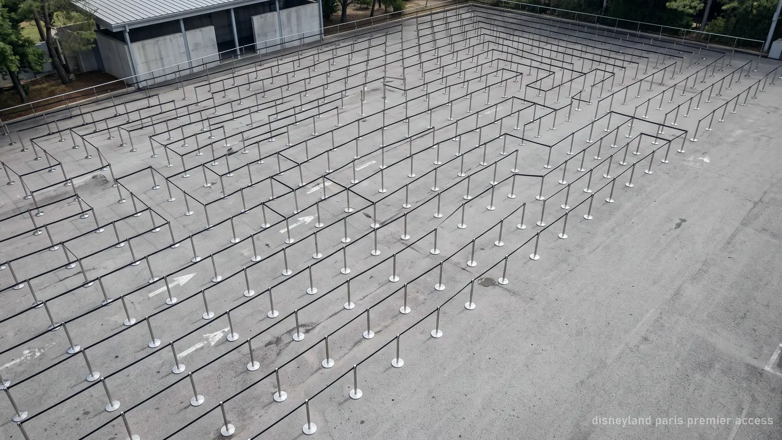 An empty switchback queue of metal barriers and retractable belts, photographed from above